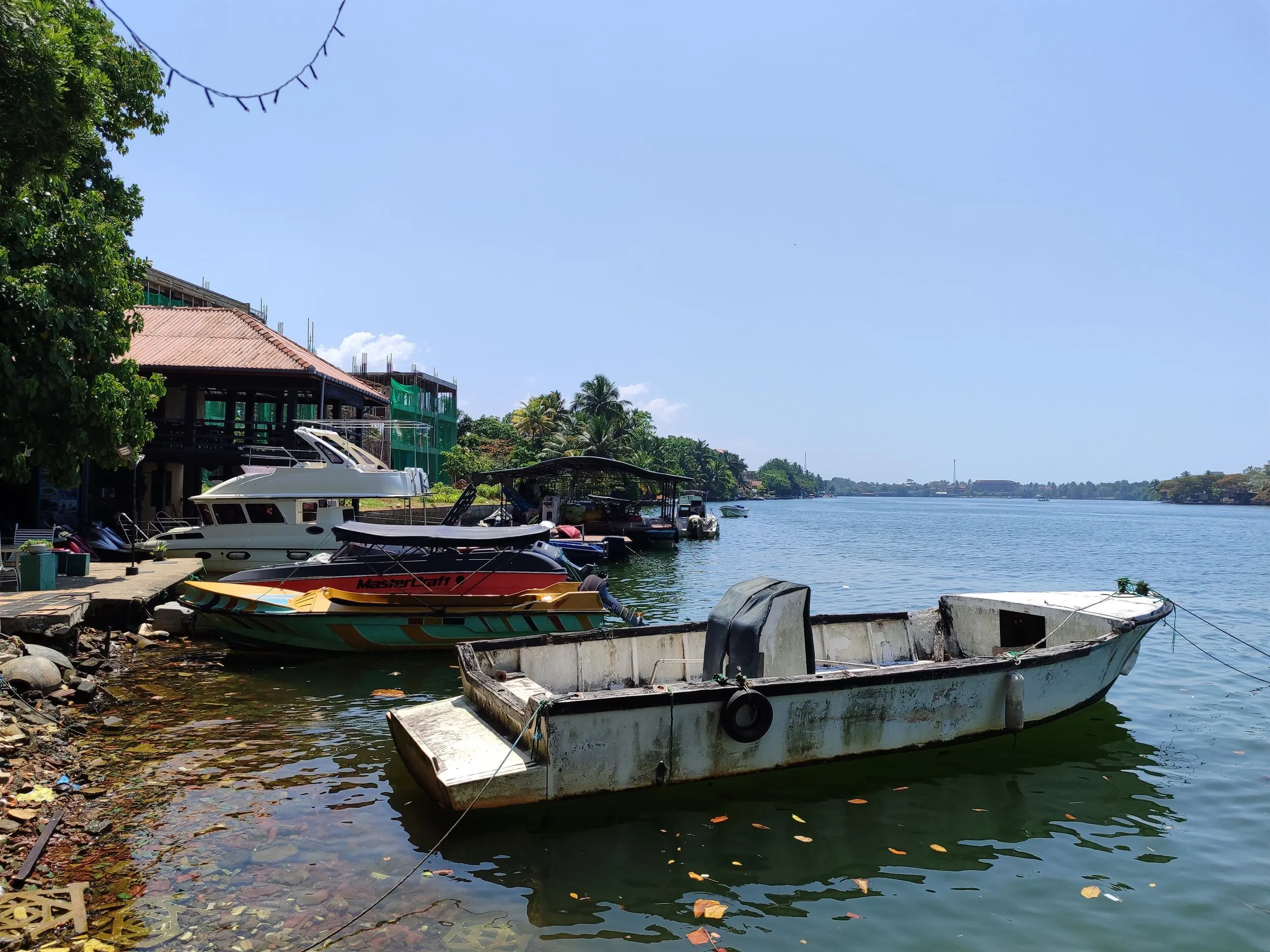 Speedboats and an old wooden outrigger tied up on the Bentota river