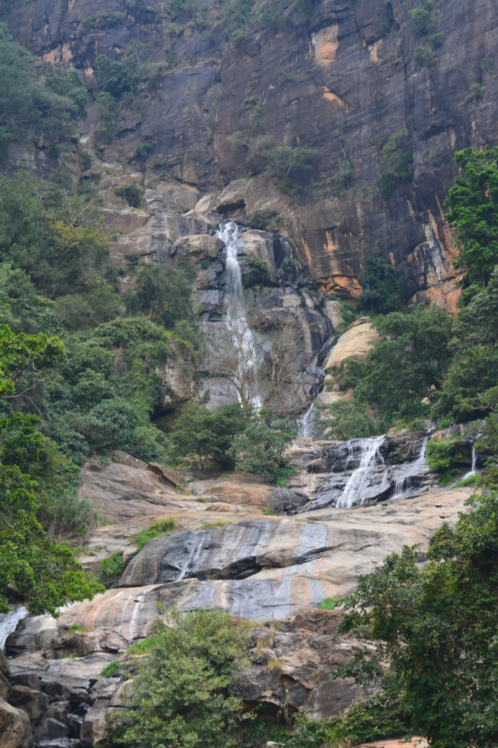 A tall waterfall falling in stages down a jungle cliff