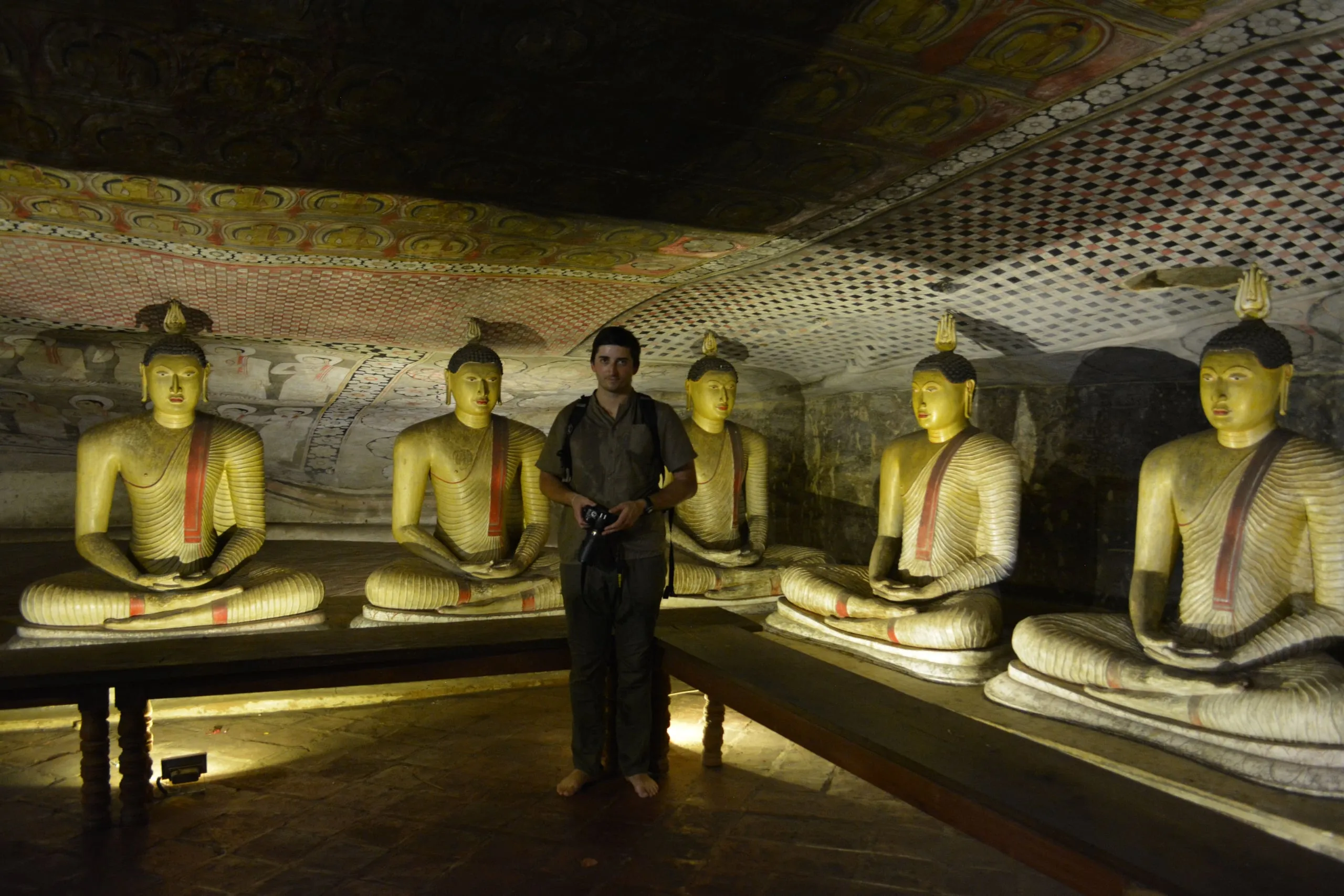 Buddha statues and painted ceiling inside a rock cave temple