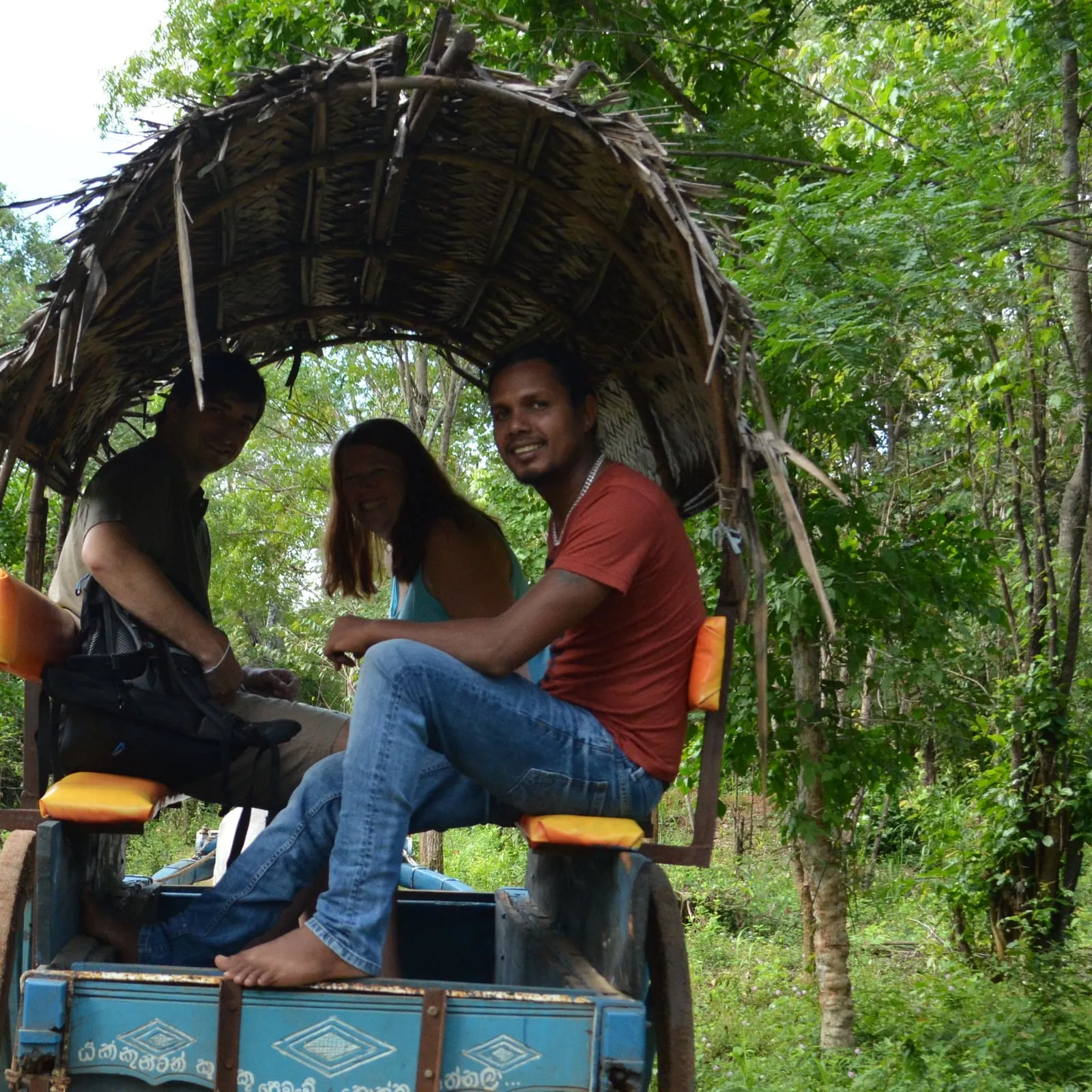 Indika riding a bullock cart with two guests