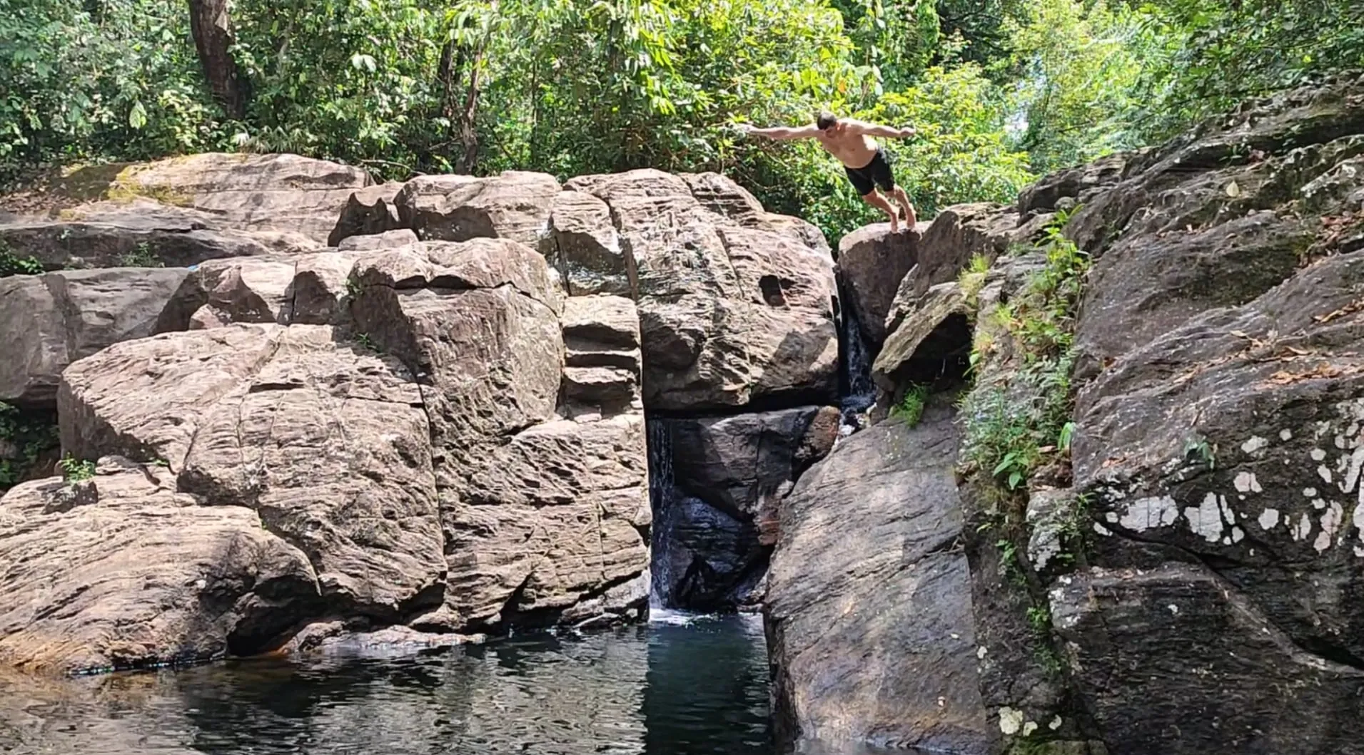 A guest jumping from a rock ledge into the pool below Polgampola waterfall