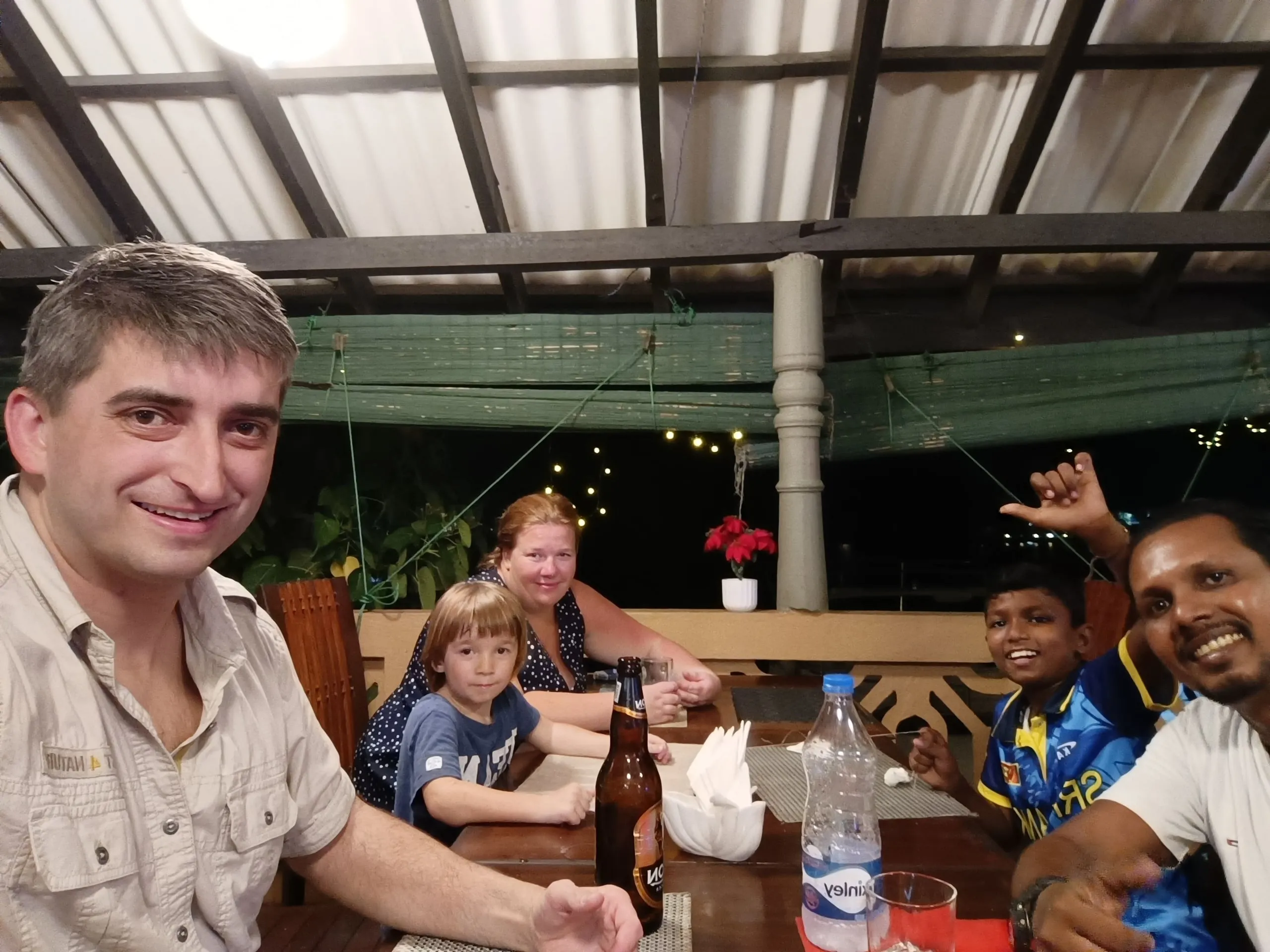 Two families around a long table at an open-sided restaurant in the evening