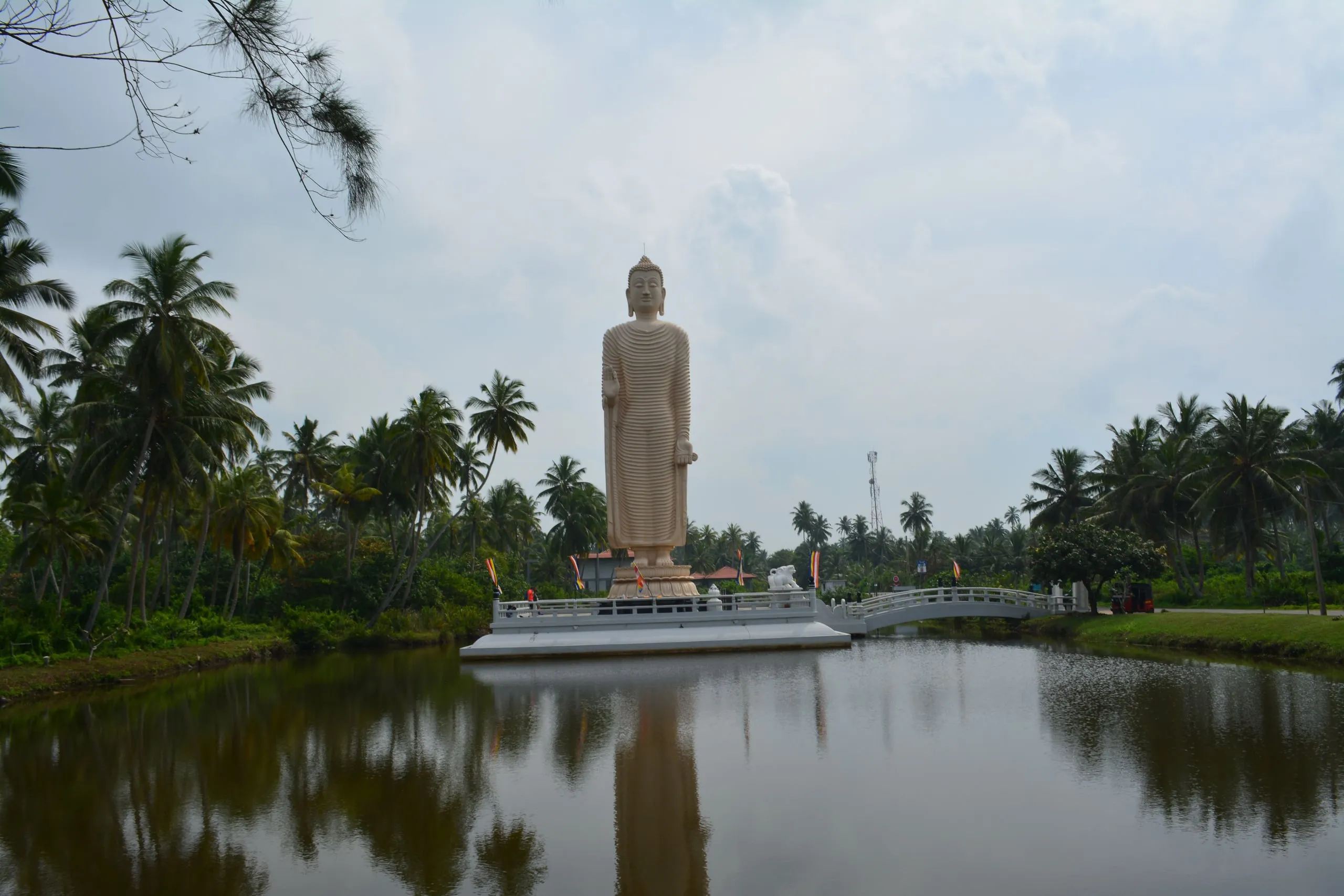 The tall standing Buddha of the tsunami monument at Peraliya, reflected in the lagoon
