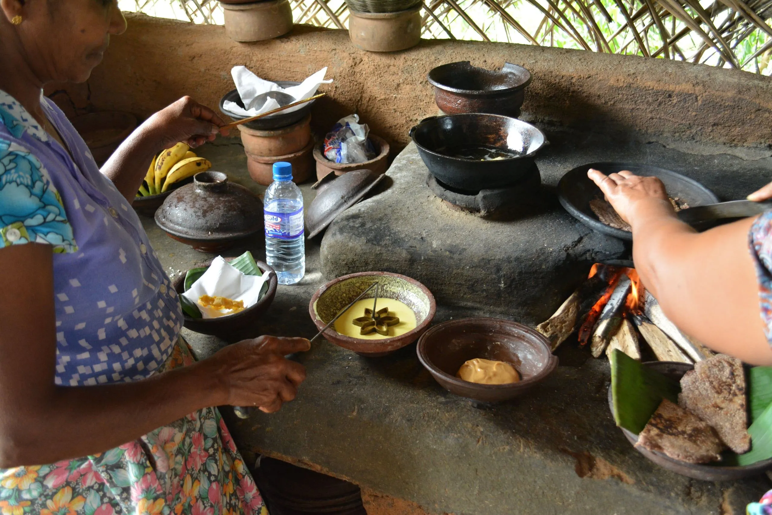 Two women cooking over the wood-fired hearth of a village kitchen